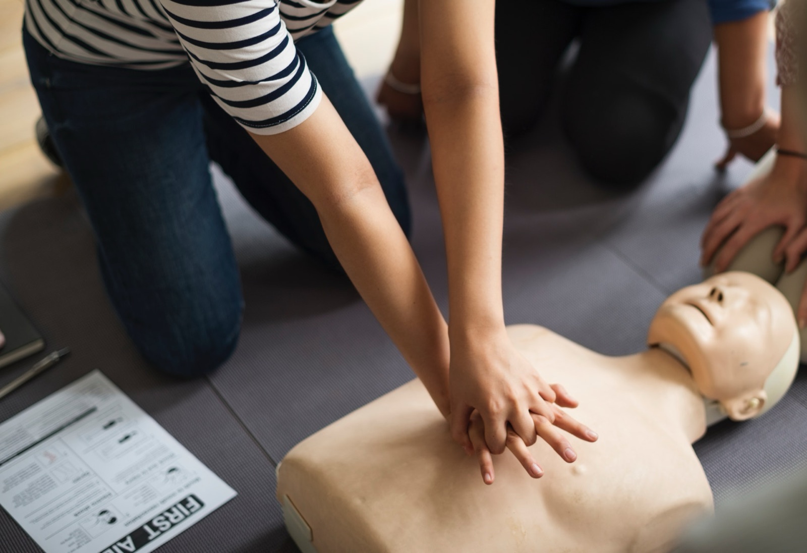 Deelnemers oefenen reanimatie op een oefenpop tijdens een EHBO-training